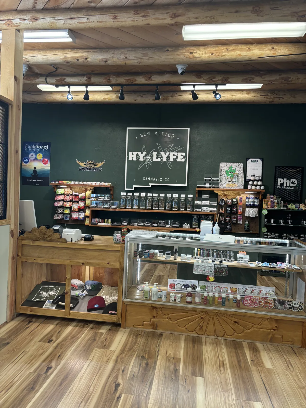 Inside NM HyLyfe: pine counter, glass jars of flower and the New Mexico shaped sign