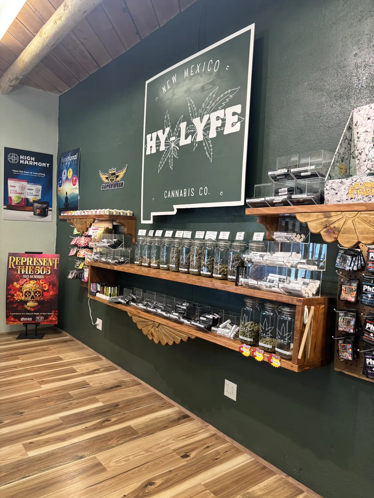 Flower jars and pre-roll shelves on the green wall at NM HyLyfe